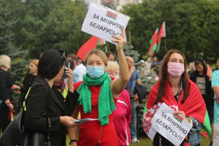 Минск. Девушки держат плакаты `За мирную Беларусь` во время митинга в поддержку президента Белоруссии Александра Лукашенко.