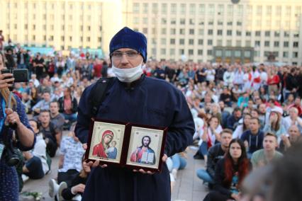 Минск. Священник держит иконы во время митинга против результатов выборов президента Белоруссии на площади Независимости, где расположены здания правительства и ЦИК.