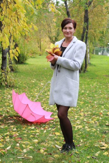 Иркутск. Девушка в парке собирает осенние листья.