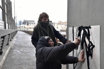 Москва. Уличный художник из проекта `После иконы` Антон Беликов вместе с командой наносит на стену граффити `Погляди на небо` с помощью трафарета.