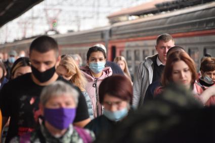 Москва. Пассажиры пригородных поездов в медицинских масках на платформе.