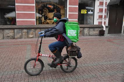 Москва. Курьер службы доставки еды  Delivery Club  на улице Старый Арбат.