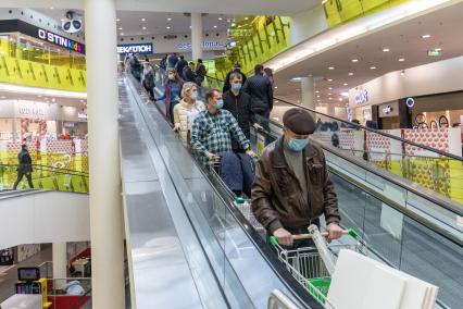 Москва.  Покупатели в защитных масках  на эскалаторе  магазина.