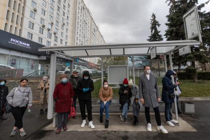 Москва.   Пассажиры на остановке общественного транспорта в медицинских масках.