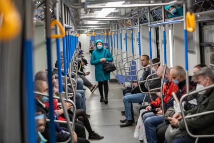 Москва. Пассажиры в защитных масках в вагоне поезда метро.