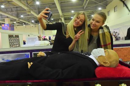 Москва. Девушки фотографируются у манекена В.И. Ленина на Международной выставке погребальных услуг `Некрополь - Tanexpo 2020` в центральном выставочном комплексе `Экспоцентр`.