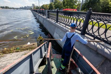 Москва.  Матрос мусоросборщика  `МС-1` собирает мусор с поверхности реки.