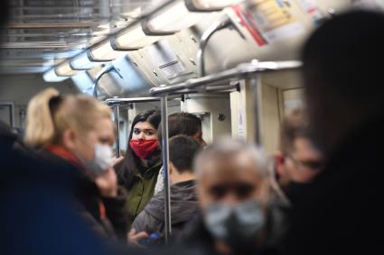 Москва.  Пассажиры в защитных масках в вагоне поезда метро.