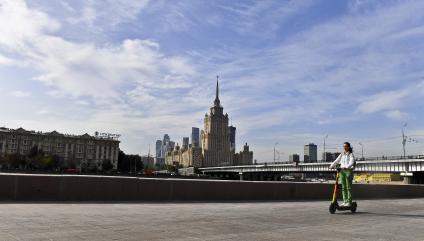 Москва.   Девушка катается на самокате  на набережной.