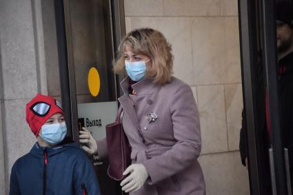 Москва. Женщина с ребенком в медицинских масках у выхода из метро.