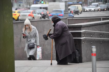 Москва. Пожилая женщина  просит милостыню у входа в метро.