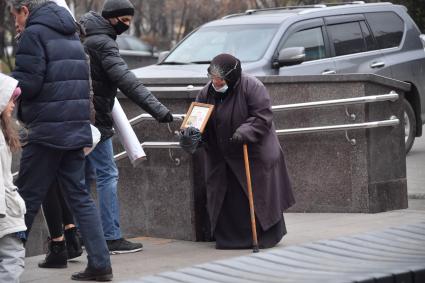 Москва. Пожилая женщина  просит милостыню у входа в метро.