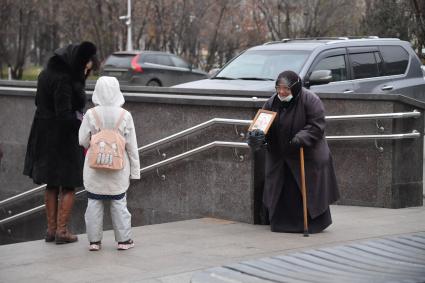 Москва. Пожилая женщина  просит милостыню у входа в метро.