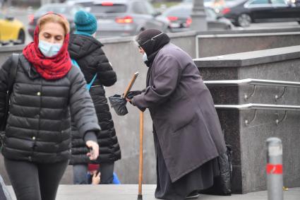 Москва. Пожилая женщина  просит милостыню у входа в метро.