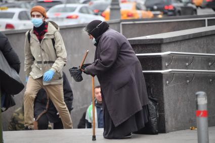 Москва. Пожилая женщина  просит милостыню у входа в метро.