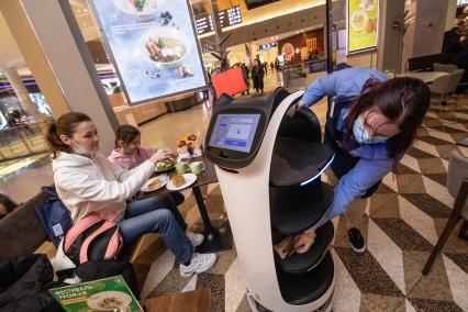 Москва. Официант рядом с роботом-официантом в кофейне `Шоколадница` во время обслуживания посетителей.