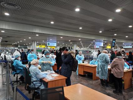 Москва.  Сотрудники санитарно-карантинного пункта в спецкостюмах и перчатках проверяют  пассажиров, прибывших в аэропорт Шереметьево из Китая.