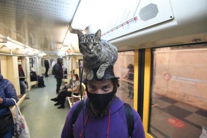 Москва. Мужчина с котом на голове в вагоне поезда метро.