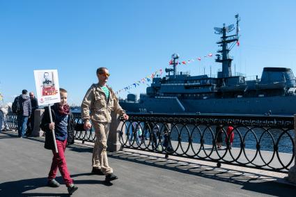 Санкт-Петербург. Мужчина с мальчиком несут портрет участника ВОВ на набережной в Санкт-Петербурге во время празднования Дня Победы.