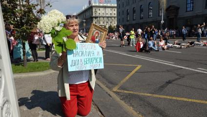 Минск. Сторонница оппозиции держит цветы, икону и плакат `Мы против насилия и лжи в Беларуси! Миру мир!` во время акции протеста. Со дня выборов президента Белоруссии 9 августа в стране прошли митинги несогласных с результатами голосования.