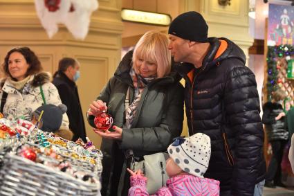 Москва.  Женщина  и мужчина покупают елочные украшения в ГУМе.