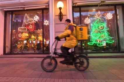 Москва.   Сотрудник сервиса доставки еды на улице города.