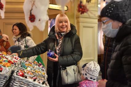 Москва.  Женщина покупает елочные украшения в ГУМе.