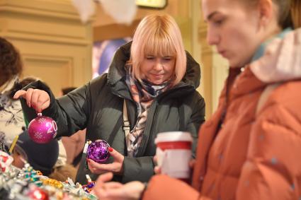 Москва.  Женщина покупает елочные украшения в ГУМе.