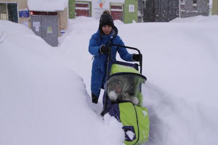 Норильск. Девушка с ребенком в коляске во время прогулки после снегопада.