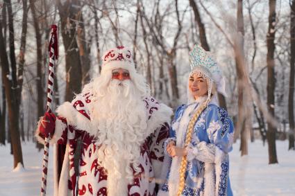 Самара. Люди в костюмах Деда Мороза и Снегурочки позируют в зимнем парке.