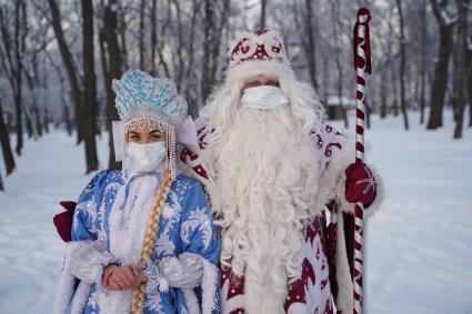 Самара. Люди в костюмах Деда Мороза и Снегурочки позируют в зимнем парке.