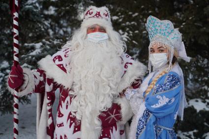 Самара. Люди в костюмах Деда Мороза и Снегурочки позируют в зимнем парке.