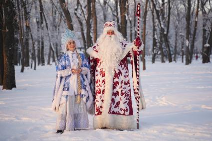 Самара. Люди в костюмах Деда Мороза и Снегурочки позируют в зимнем парке.