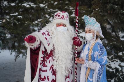 Самара. Люди в костюмах Деда Мороза и Снегурочки позируют в зимнем парке.