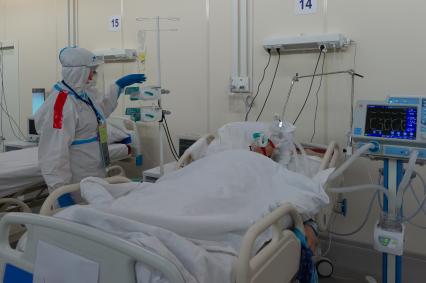 Санкт-Петербург. Медицинский работник и пациент в отделении реанимации и интенсивной терапии во временном госпитале для больных COVID-19, организованном в выставочном комплексе `Ленэкспо`.