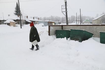 Барнаул. Женщина выкидывает мусор в уличные контейнеры, заваленные снегом.