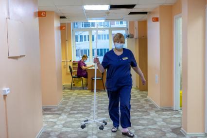 Санкт-Петербург. Медсестра несет стойку для капельницы в поликлинике N102.