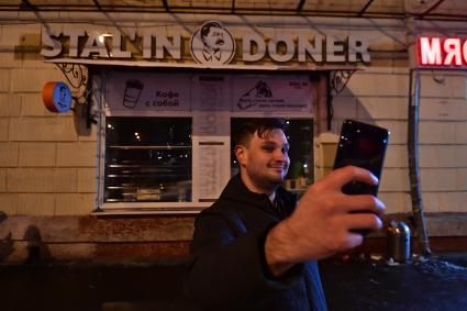 Москва. Мужчина делает селфи на фоне шаурмячной Stal’in Doner.