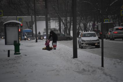 Москва. Мужчина с ребенком идут по заснеженному тротуару.