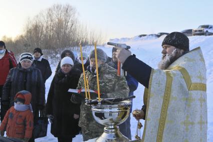 Барнаул. Батуюшка зажигает свечи во время обряда освящения воды на реки Оби в праздник Крещения Господня.