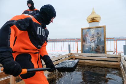 Санкт-Петербург. Санкт-Петербург. Спасатель очищает прорубь от льда перед началом крещенских купаний в купели у Петропавловской крепости.