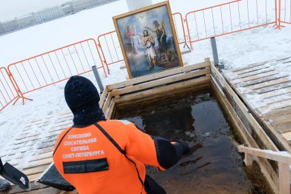 Санкт-Петербург. Санкт-Петербург. Спасатель очищает прорубь от льда перед началом крещенских купаний в купели у Петропавловской крепости.