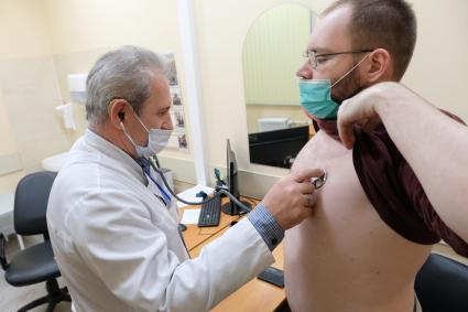 Санкт-Петербург. Врач осматривает мужчину перед вакцинацией от коронавирусной инфекции в поликлинике.