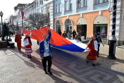 Крым. Молодые люди несут Российский флаг по улице города во время фестиваля `Крымская весна`посвященного 5-летию Общекрымского референдума 2014 года и воссоединения Крыма с Россией.