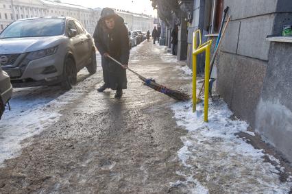 Санкт-Петербург. Пожилая женщина подметает заснеженную улицу.