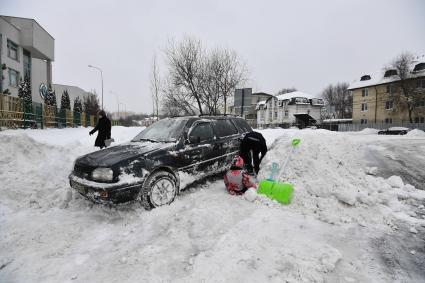 Москва. Мужчина расчищает автомобиль от снега.