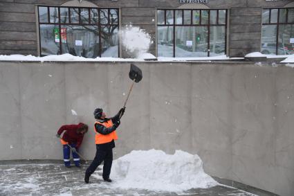 Москва. Дворник скидывает снег из перехода на тротуар.