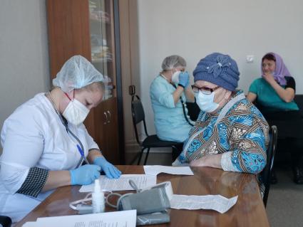 Самарская область, с. Рождествено.   Врач осматривает женщину перед вакцинацией от коронавирусной инфекции в поликлинике.