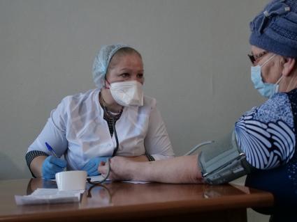 Самарская область, с. Рождествено. Врач осматривает женщину перед вакцинацией от коронавирусной инфекции в поликлинике.