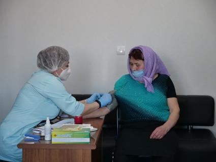 Самарская область, с. Рождествено.  Врач осматривает женщину перед вакцинацией от коронавирусной инфекции в поликлинике.